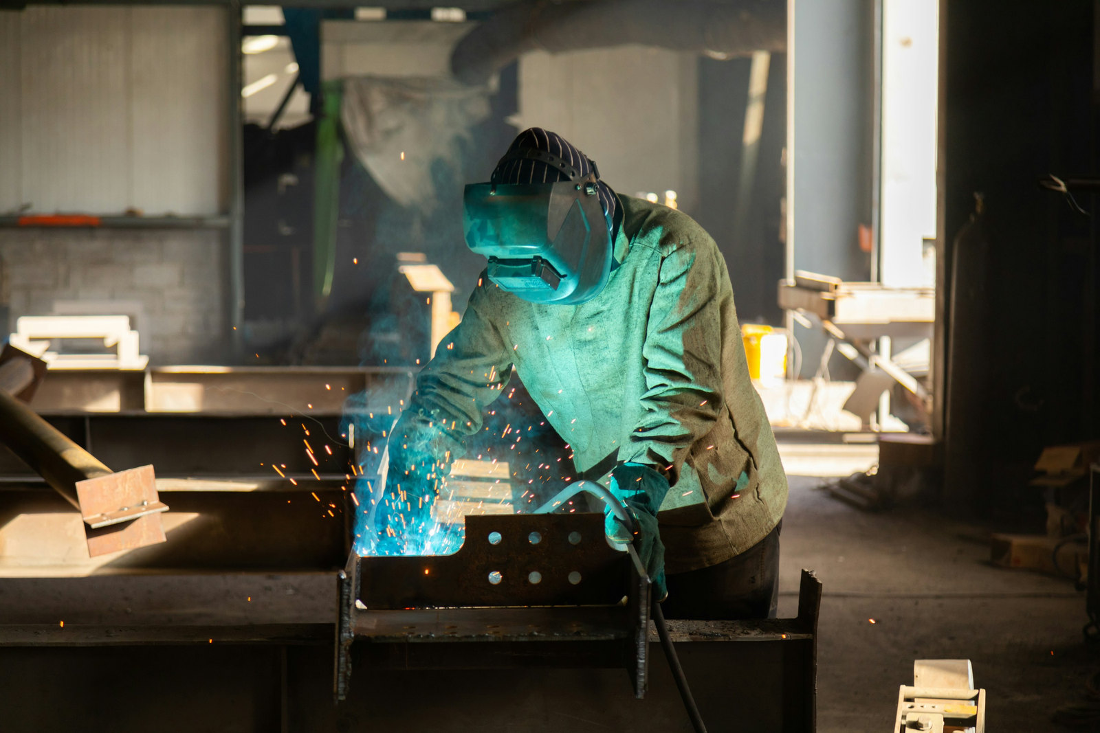 Welder fabricating a steel assembly in a metal fabrication workshop